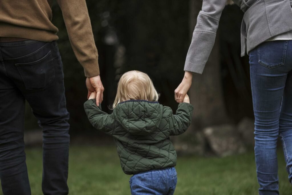 Bambino felice con più figure genitoriali accanto Bambino felice con più figure genitoriali accanto
